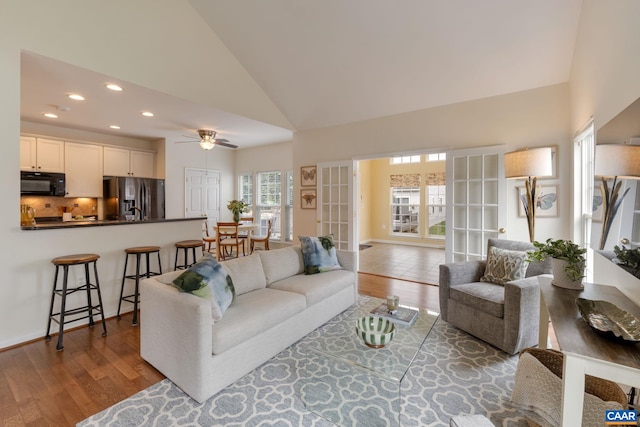 living room featuring wood-type flooring, high vaulted ceiling, and ceiling fan