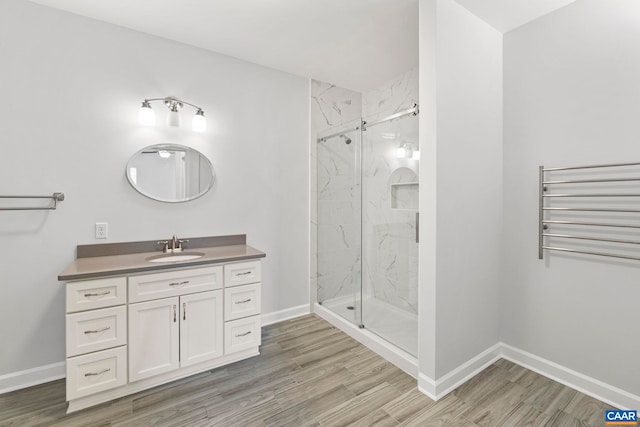 bathroom with hardwood / wood-style flooring, vanity, and a shower with door