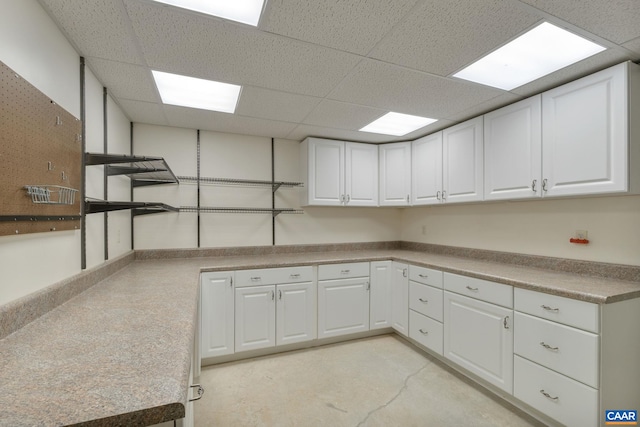 kitchen featuring a drop ceiling and white cabinets