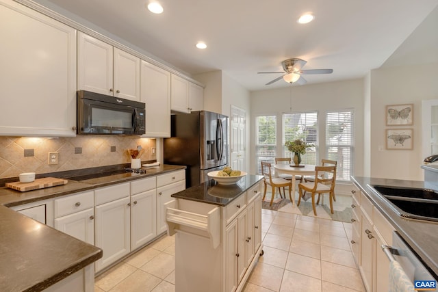 kitchen with light tile patterned flooring, tasteful backsplash, a kitchen island, and black appliances