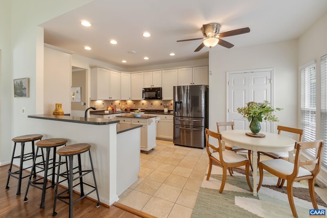 kitchen with white cabinets, a breakfast bar, stainless steel fridge, and kitchen peninsula