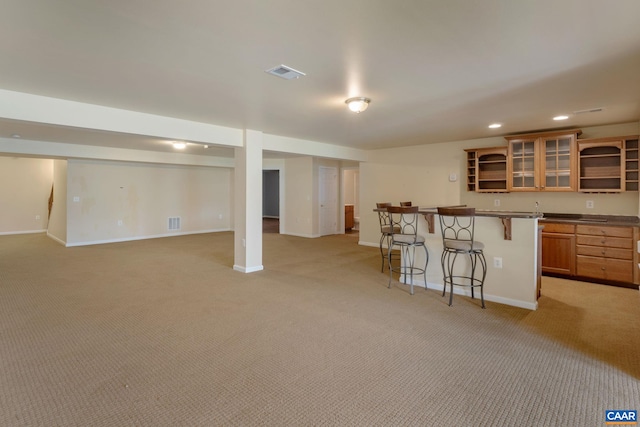 basement featuring light colored carpet and indoor bar