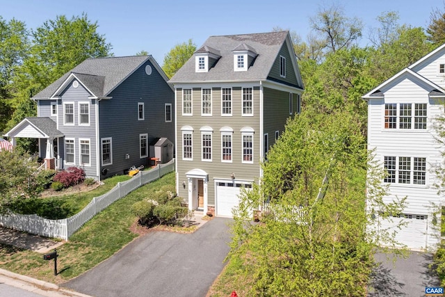 view of front facade with asphalt driveway, a garage, and fence