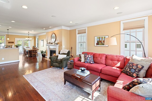 living area featuring ornamental molding, dark wood finished floors, recessed lighting, a fireplace with flush hearth, and a chandelier