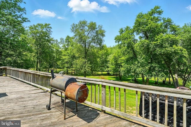  - deck with a lawn, area for grilling, and view of wooded area