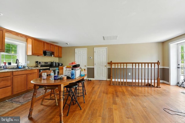  - kitchen with black microwave, stainless steel electric stove, a sink, light wood-style flooring, and healthy amount of natural light