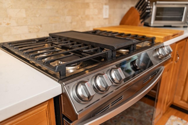 3953 Cavalry Ln, Penn Laird, VA 22846 - kitchen view of stainless steel gas stove, backsplash, brown cabinets, and light countertops