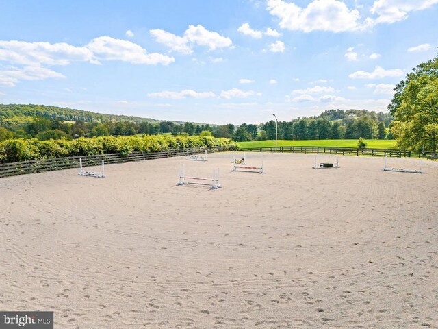 view of community with an enclosed riding area and a wooded view