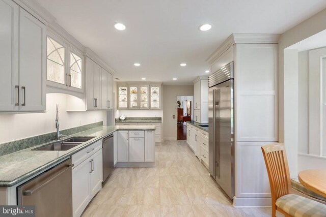 kitchen with appliances with stainless steel finishes, a sink, recessed lighting, white cabinetry, and glass insert cabinets