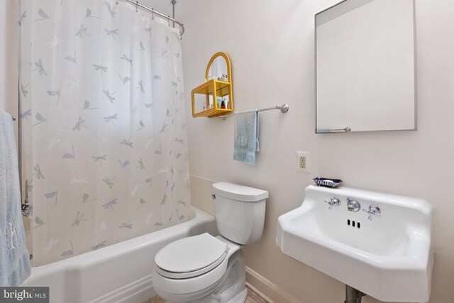 full bathroom featuring toilet, shower / tub combo with curtain, baseboards, and a sink