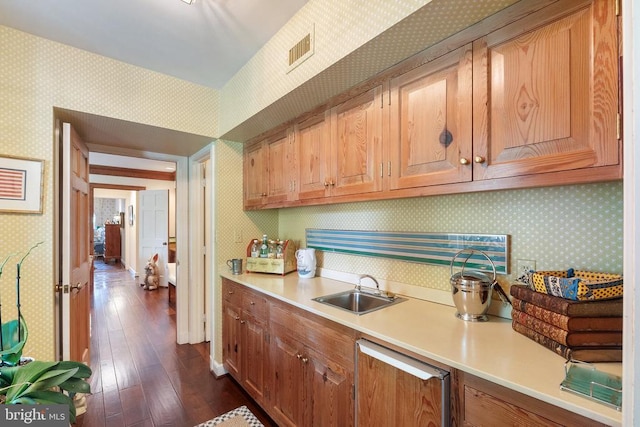 kitchen featuring wallpapered walls, a sink, light countertops, and dark wood-style floors