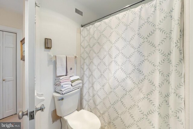bathroom with toilet and curtained shower