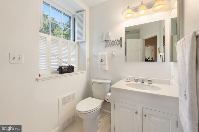 bathroom featuring radiator heating unit, baseboards, toilet, vanity, and tile patterned flooring