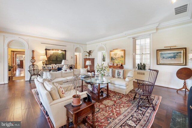 living area with crown molding, arched walkways, dark wood-style flooring, and baseboards