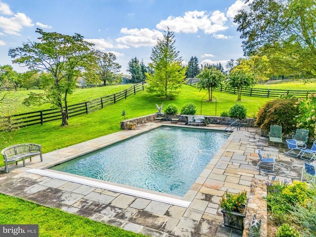 view of pool with a patio and a rural view