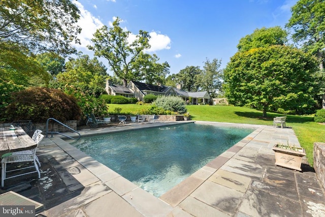swimming pool with a patio and a lawn