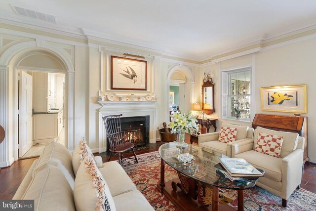 living room with crown molding, wood finished floors, and a fireplace with flush hearth