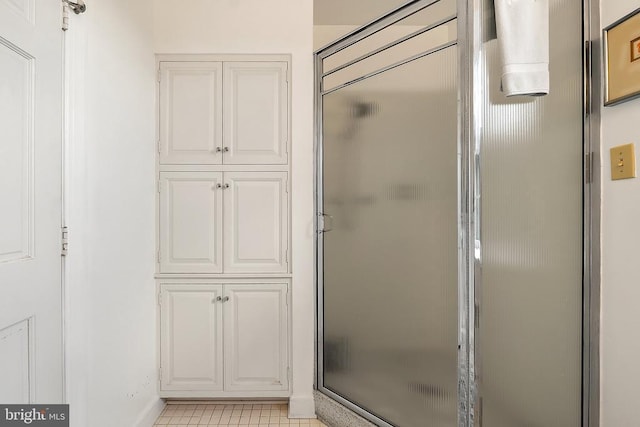 full bath featuring a stall shower, tile patterned floors, and baseboards