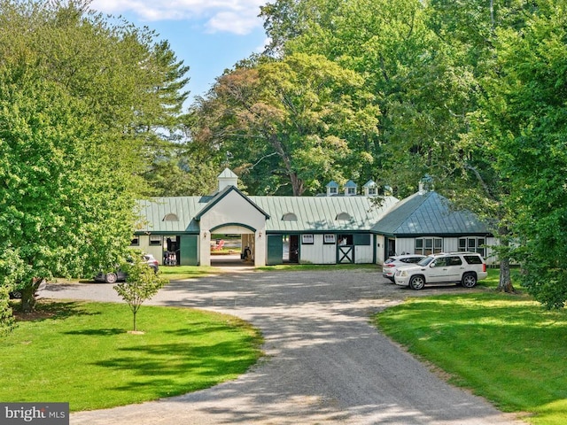 view of front of home featuring a standing seam roof, a front yard, metal roof, and curved driveway