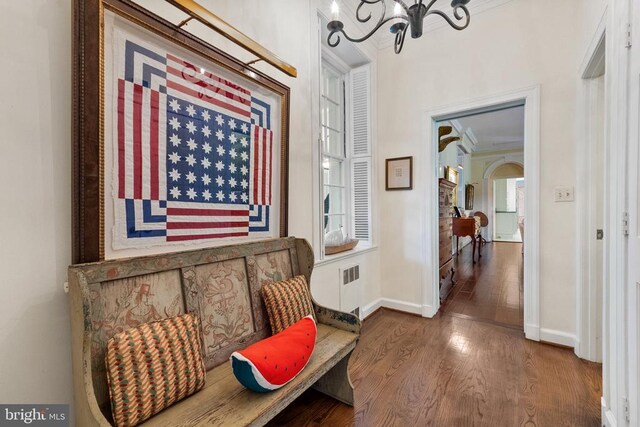 living area featuring ornamental molding, wood finished floors, a chandelier, baseboards, and radiator heating unit