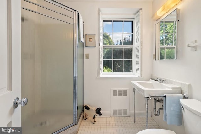 bathroom featuring radiator, toilet, a shower stall, tile patterned flooring, and baseboards