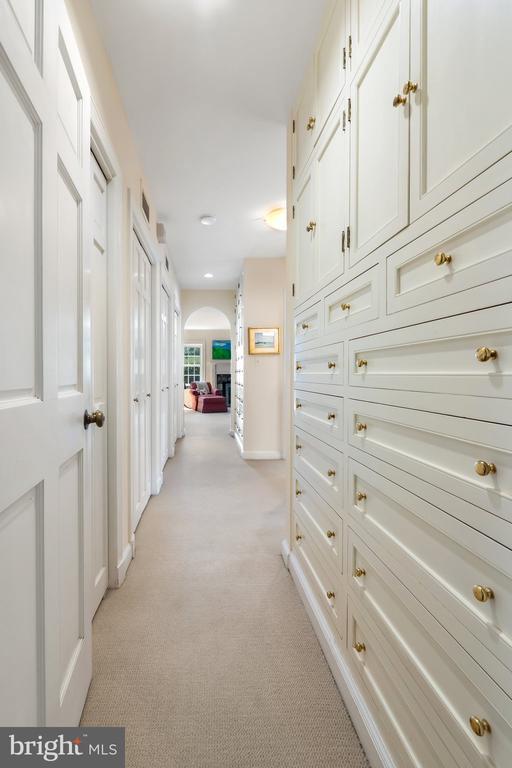 hallway featuring light carpet, arched walkways, and baseboards