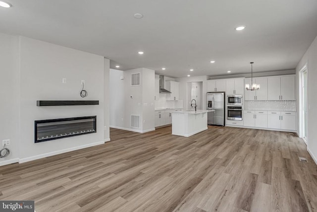 35607 Pine Needle Ln, Locust Grove, VA 22508 - unfurnished living room with a glass covered fireplace, light wood-style flooring, recessed lighting, a chandelier, and baseboards