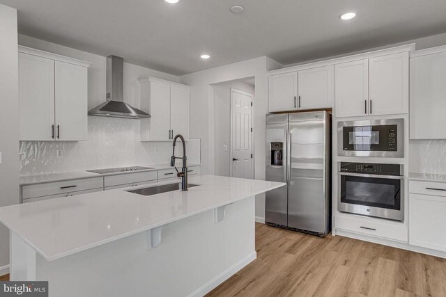 35607 Pine Needle Ln, Locust Grove, VA 22508 - kitchen with stainless steel appliances, wall chimney range hood, light wood-style floors, a sink, and decorative backsplash