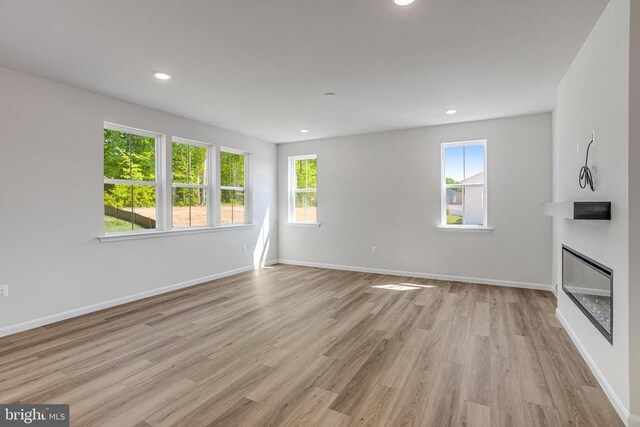 35607 Pine Needle Ln, Locust Grove, VA 22508 - unfurnished living room with healthy amount of natural light, light wood-type flooring, a glass covered fireplace, baseboards, and recessed lighting