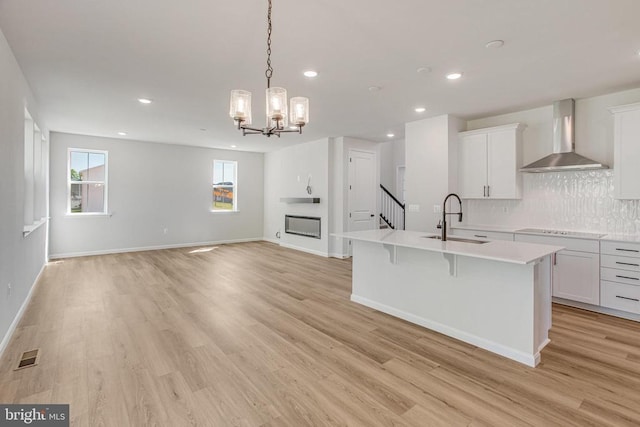 35607 Pine Needle Ln, Locust Grove, VA 22508 - kitchen featuring a sink, wall chimney exhaust hood, electric stovetop, a center island with sink, and light wood-type flooring
