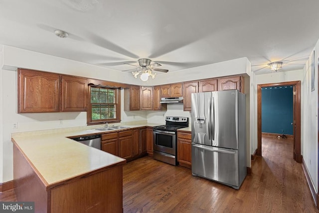  - kitchen with appliances with stainless steel finishes, extractor fan, brown cabinets, and light countertops