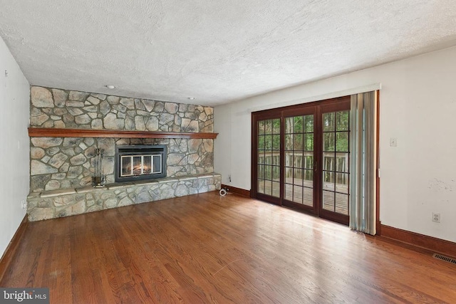  - unfurnished living room featuring wood finished floors, a textured ceiling, and a fireplace