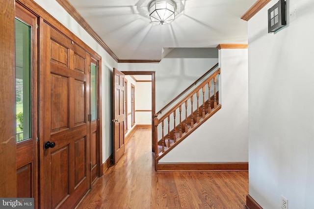  - entryway with wood finished floors, stairs, and ornamental molding