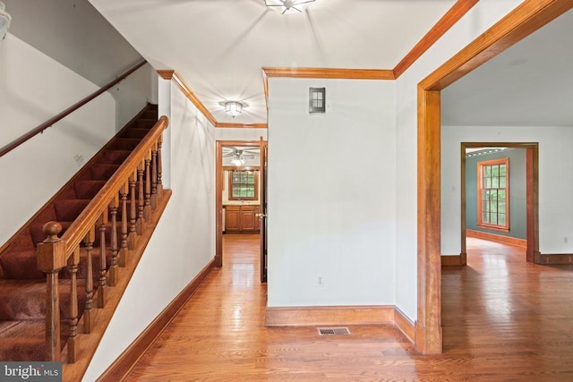  - corridor with crown molding, wood finished floors, and stairs