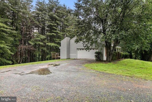  - view of property exterior with a chimney, a yard, and a garage