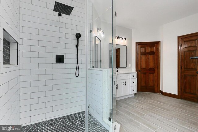  - bathroom featuring tiled shower, vanity, and wood finished floors