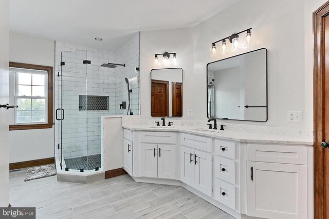  - bathroom with a shower stall, double vanity, and wood finished floors