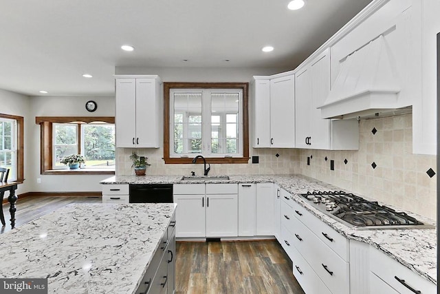  - kitchen featuring stainless steel gas cooktop, custom range hood, dark wood-style floors, white cabinets, and light stone counters