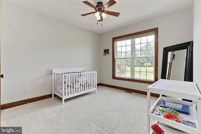  - carpeted bedroom with a nursery area and ceiling fan