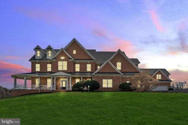 view of front of house with a yard, brick siding, and covered porch