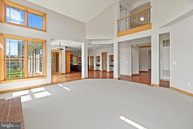 unfurnished living room with baseboards, a high ceiling, carpet, and wood finished floors