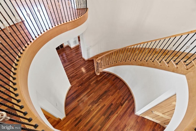 stairway with wood finished floors, baseboards, and a towering ceiling