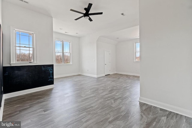 unfurnished living room with healthy amount of natural light, baseboards, and a ceiling fan