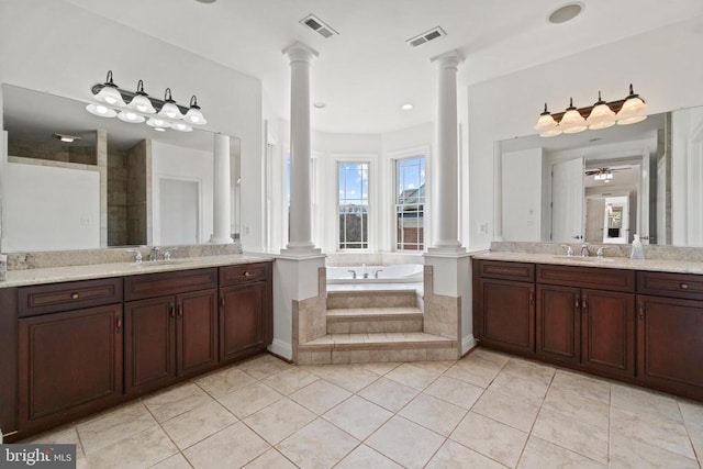 bathroom featuring decorative columns, a garden tub, tile patterned floors, and two vanities