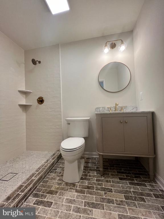 377 Cleveland St, Warrenton, VA 20186 - full bathroom featuring a tile shower, vanity, and brick patterned flooring