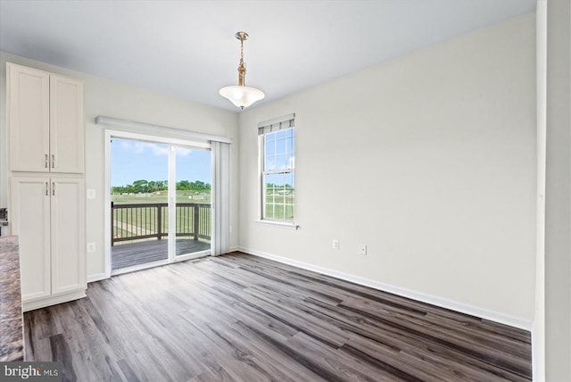 unfurnished dining area with dark wood-style floors and baseboards