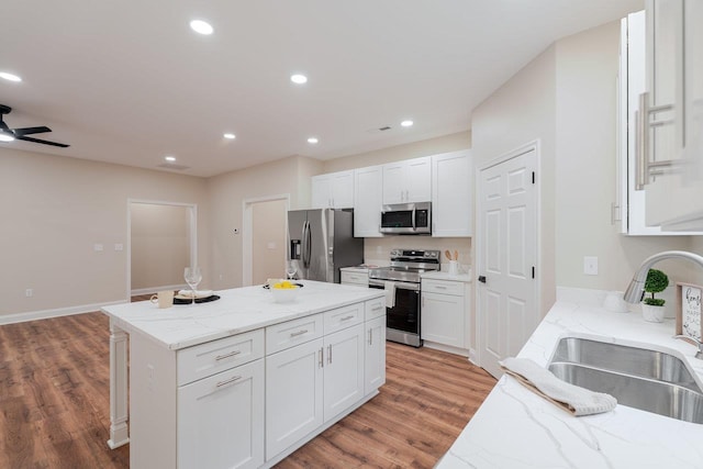 1101 Aspen Ave Unit 1101, Grottoes, VA 24441 - kitchen featuring stainless steel appliances, a sink, light wood-style floors, a center island, and white cabinetry