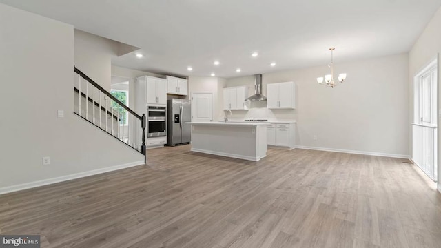 11796 Wales Dr, Fredericksburg, VA 22407 - kitchen with appliances with stainless steel finishes, wall chimney exhaust hood, open floor plan, a chandelier, and white cabinetry