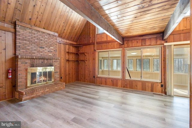 unfurnished living room with lofted ceiling with beams, wood finished floors, wooden ceiling, wood walls, and a fireplace