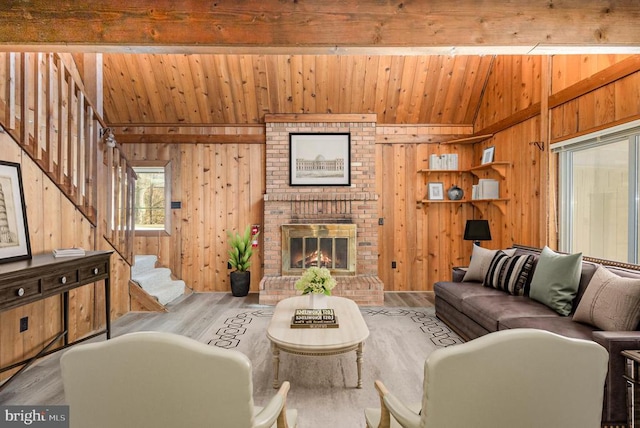 living room featuring wooden walls, stairs, lofted ceiling with beams, and wood finished floors